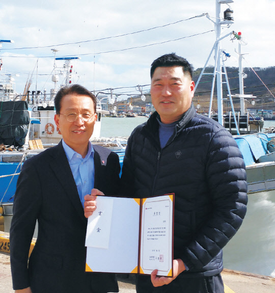 2일 전남 목포북항에 정박 중인 현진호 앞에서 김국관 선장(오른쪽)에게 남상건 LG복지재단 부사장이 'LG 의인상'과 그물 수리비를 포함한 상금 3000만원을 전달했다.  LG 제공